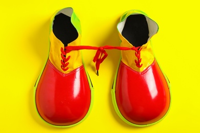 Pair of clown's shoes on yellow background, flat lay