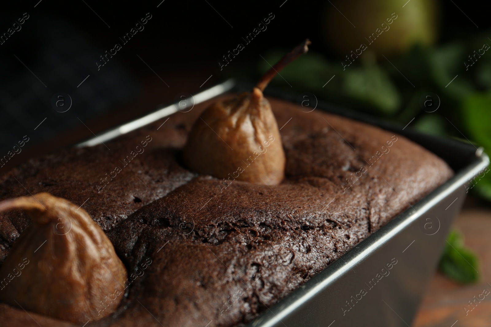 Photo of Tasty pear bread in baking form on table, closeup. Homemade cake