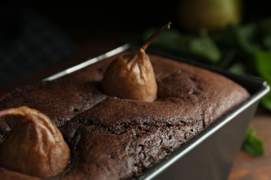 Photo of Tasty pear bread in baking form on table, closeup. Homemade cake