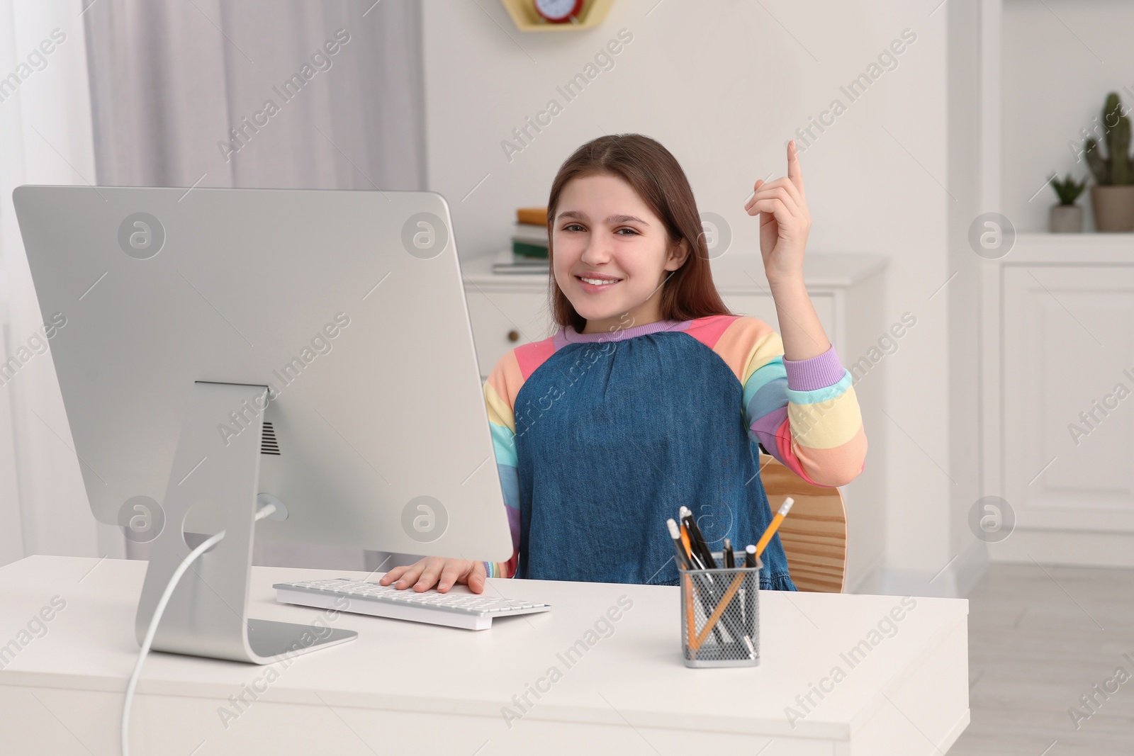 Photo of Cute girl using computer at desk in room. Home workplace