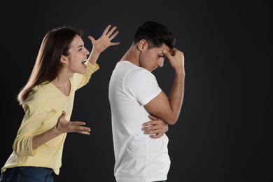 Photo of Woman shouting at her boyfriend on black background. Relationship problems