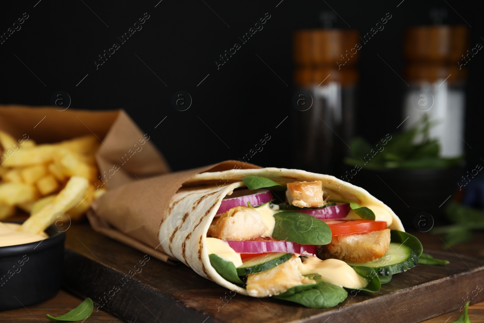 Photo of Delicious shawarma with chicken meat, fresh vegetables and spinach on wooden table, closeup