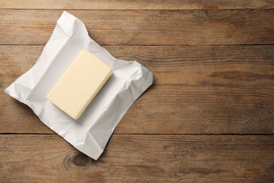 Photo of Block of tasty butter on wooden table, top view. Space for text