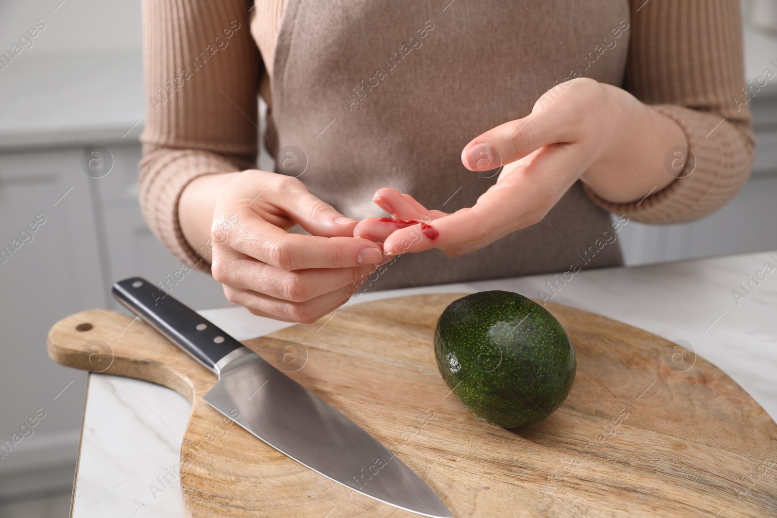 Photo of Woman cut finger while cooking in kitchen, closeup