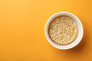 Photo of Cup of instant noodles on color background, top view. Space for text