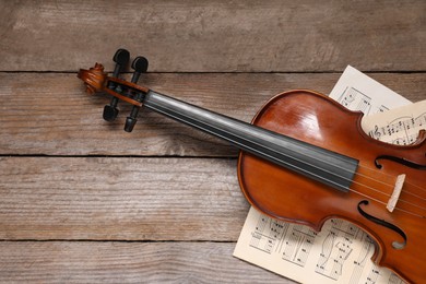 Violin and music sheets on wooden table, top view. Space for text