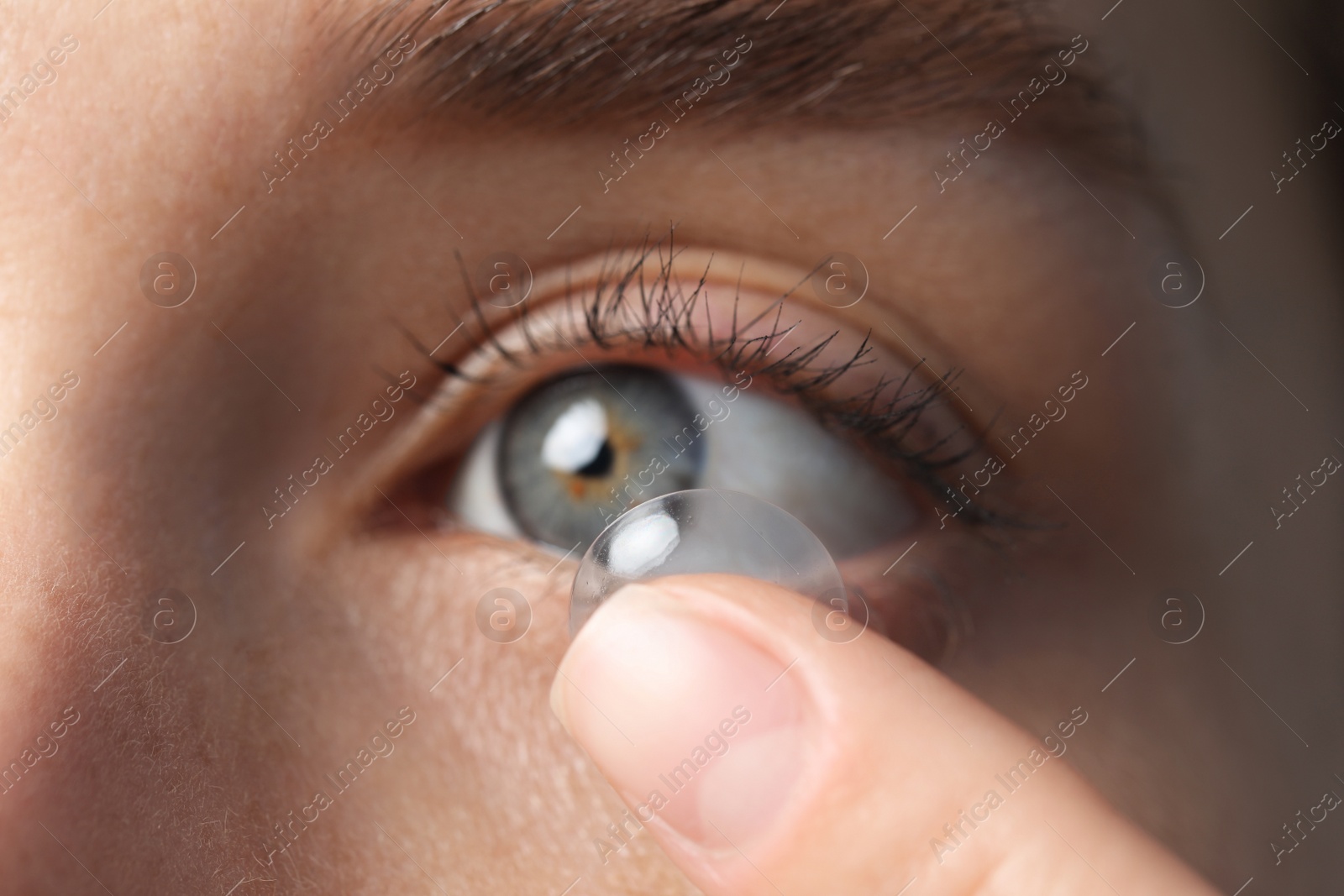 Photo of Woman putting in contact lens, closeup view