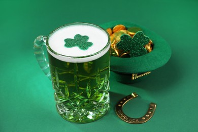 Photo of St. Patrick's day party. Green beer, leprechaun hat with gold, horseshoe and decorative clover leaves on green background