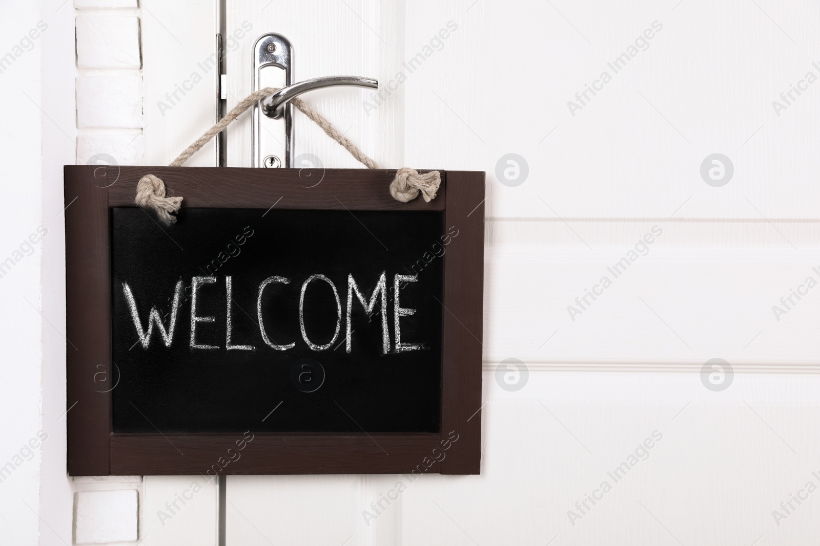 Photo of Small chalkboard with word Welcome hanging on door handle, space for text