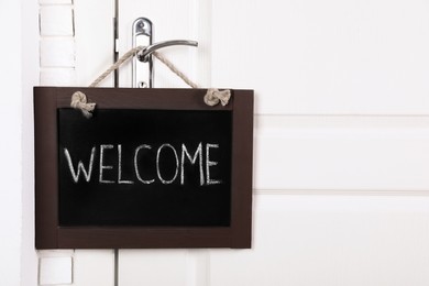Photo of Small chalkboard with word Welcome hanging on door handle, space for text