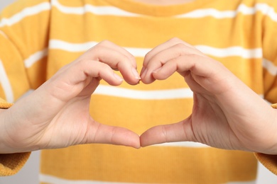 Photo of Young woman making heart with her hands, closeup view