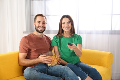 Photo of Young couple watching TV on sofa at home