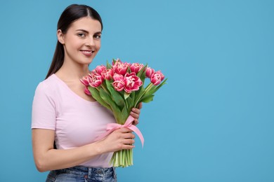 Photo of Happy young woman with beautiful bouquet on light blue background. Space for text