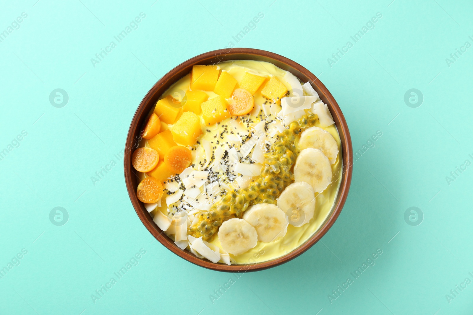 Photo of Tasty smoothie bowl with fresh fruits on turquoise background, top view