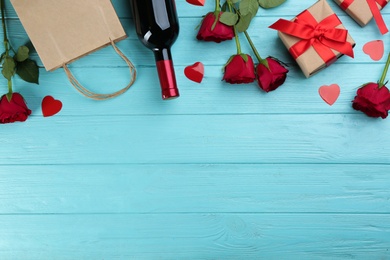 Photo of Flat lay composition with gift box and roses on turquoise wooden background, space for text. Valentine's Day celebration