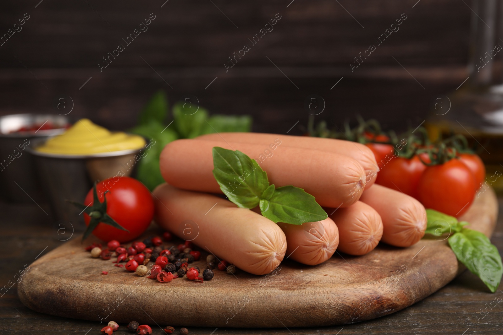 Photo of Delicious boiled sausages, tomatoes, basil and peppercorns on wooden table, closeup