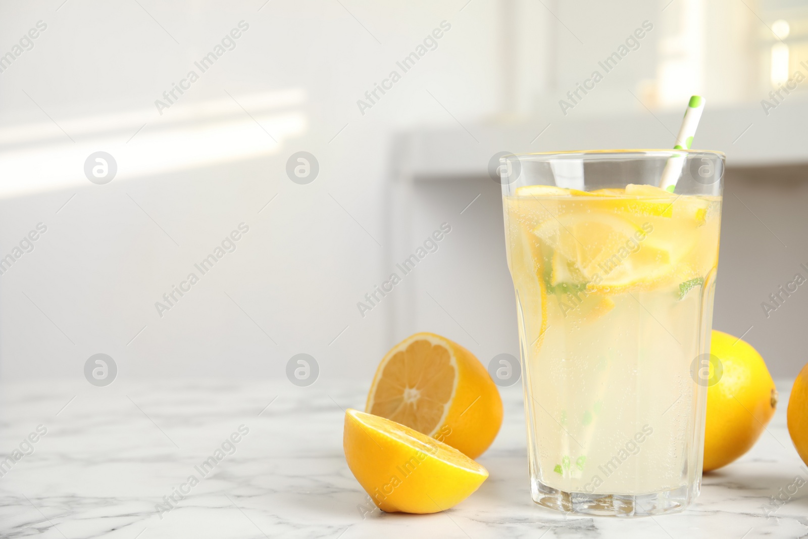 Photo of Cool freshly made lemonade and fruits on white marble table. space for text