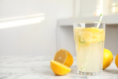 Photo of Cool freshly made lemonade and fruits on white marble table. space for text