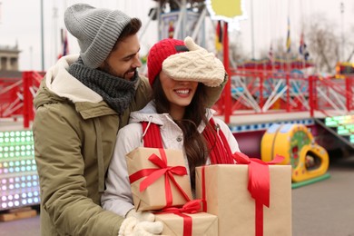 Photo of Lovely couple with Christmas presents in amusement park