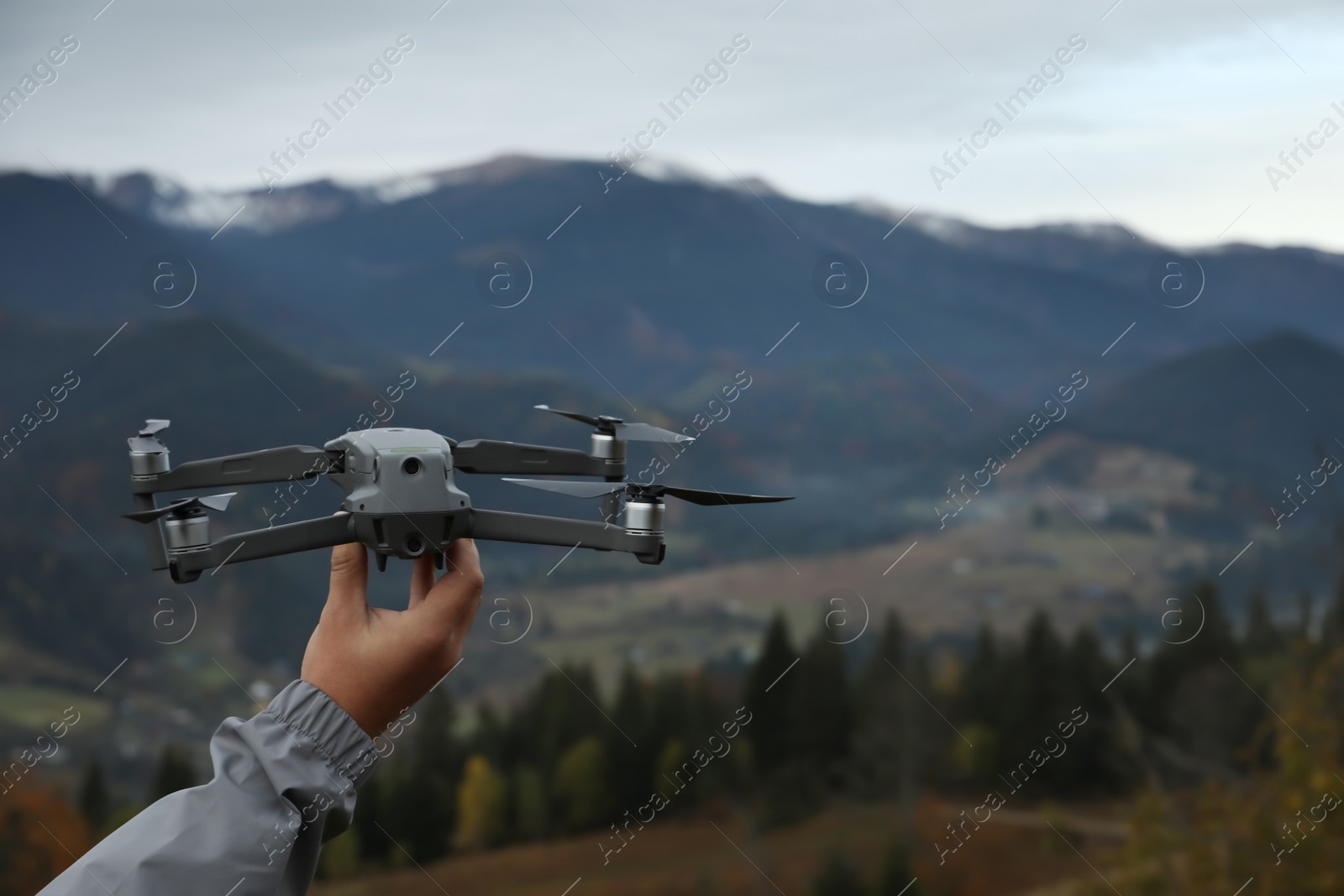 Photo of Man with modern drone in mountains, closeup. Space for text