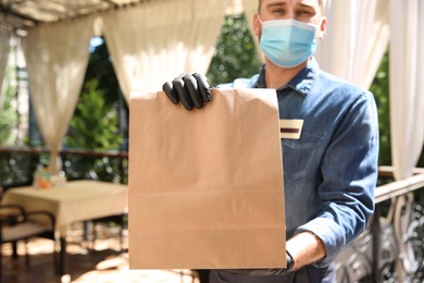 Photo of Waiter with packed takeout order in restaurant. Food service during coronavirus quarantine