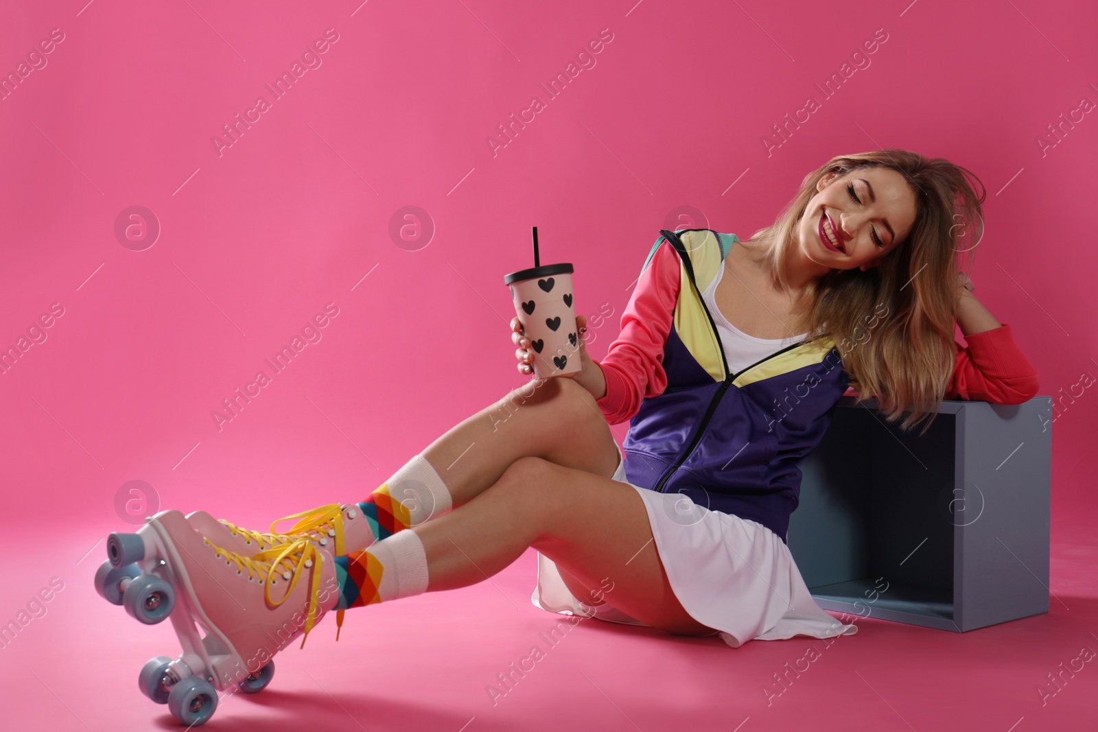 Photo of Young woman with retro roller skates and cup of drink on color background