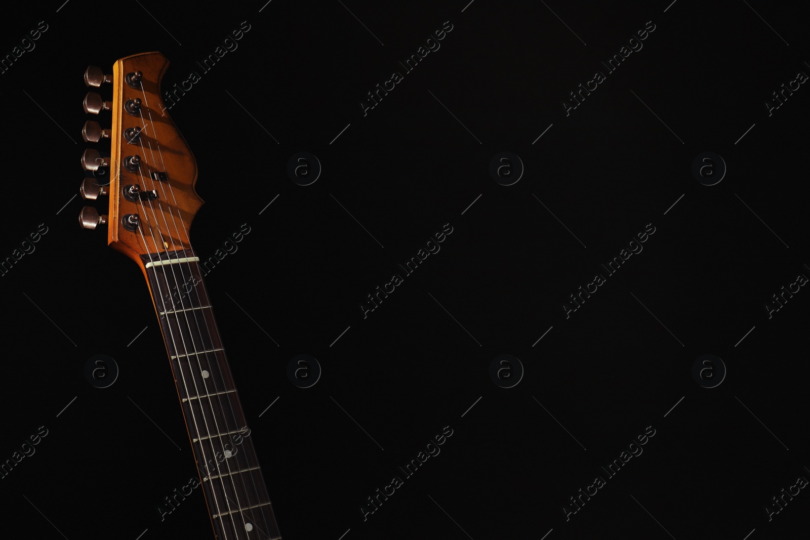Photo of Electric guitar on black background. Space for text