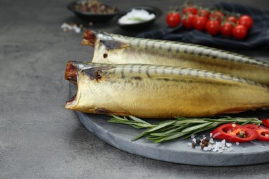 Delicious smoked mackerels and spices on dark grey table, closeup