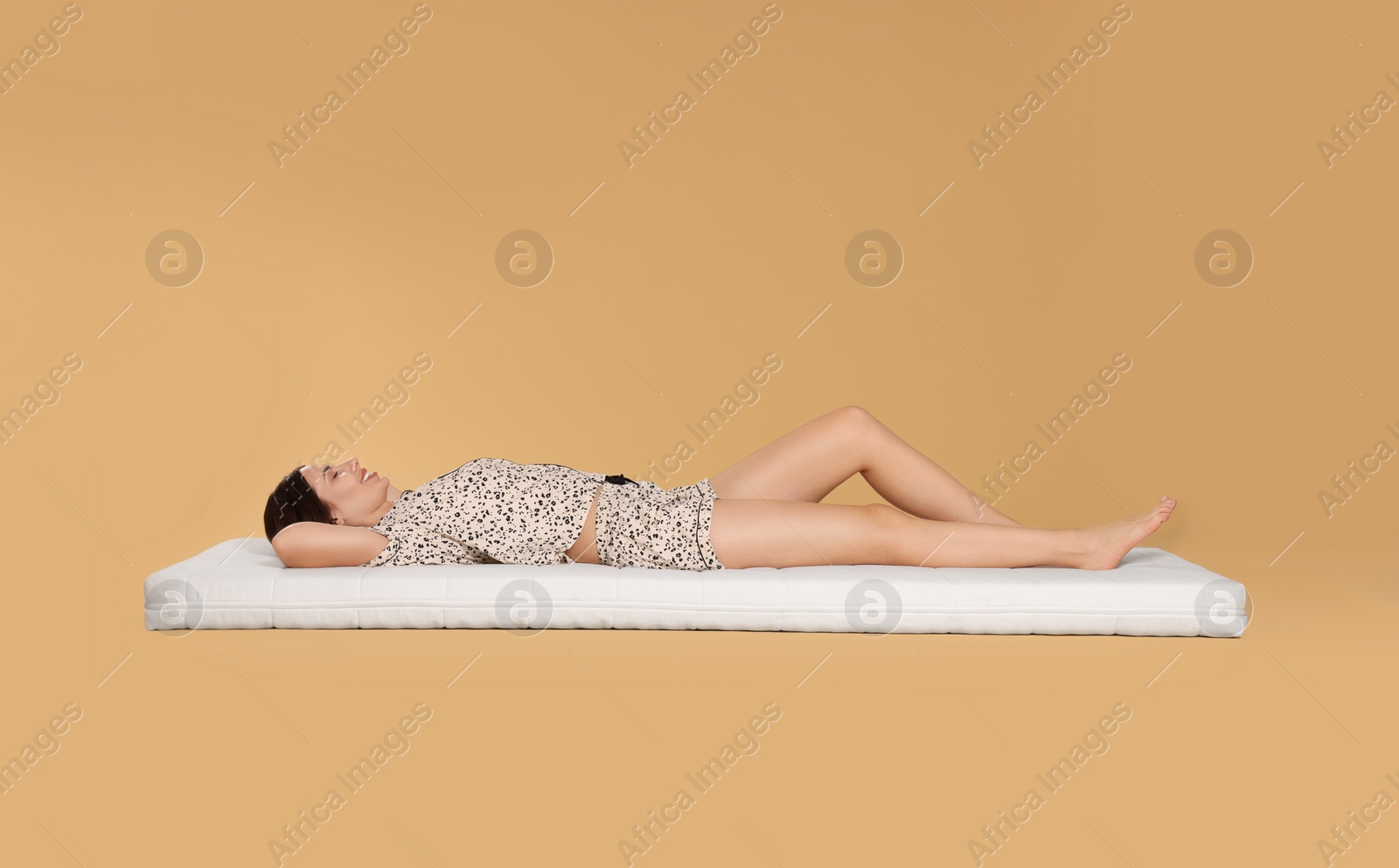 Photo of Young woman sleeping on soft mattress against beige background