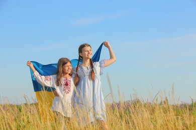 Photo of Happy girls with national flag of Ukraine in field. Space for text