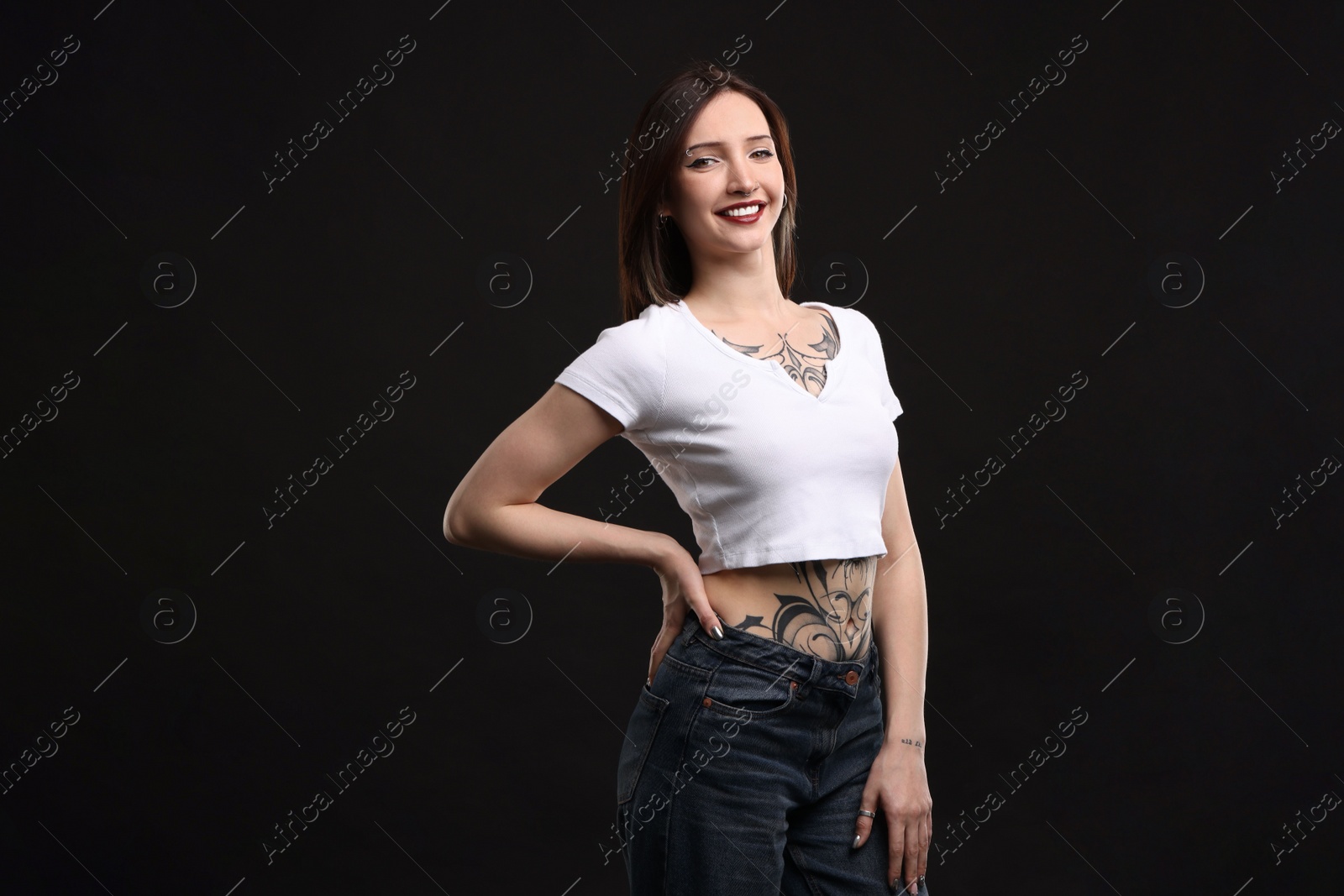 Photo of Portrait of smiling tattooed woman on black background