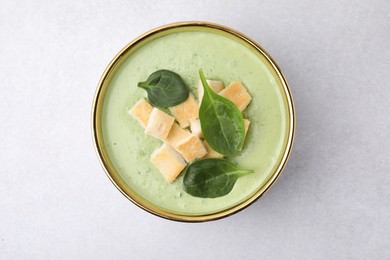 Delicious spinach cream soup with croutons in bowl on light grey table, top view