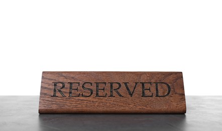 Photo of Elegant wooden sign Reserved on grey table against white background