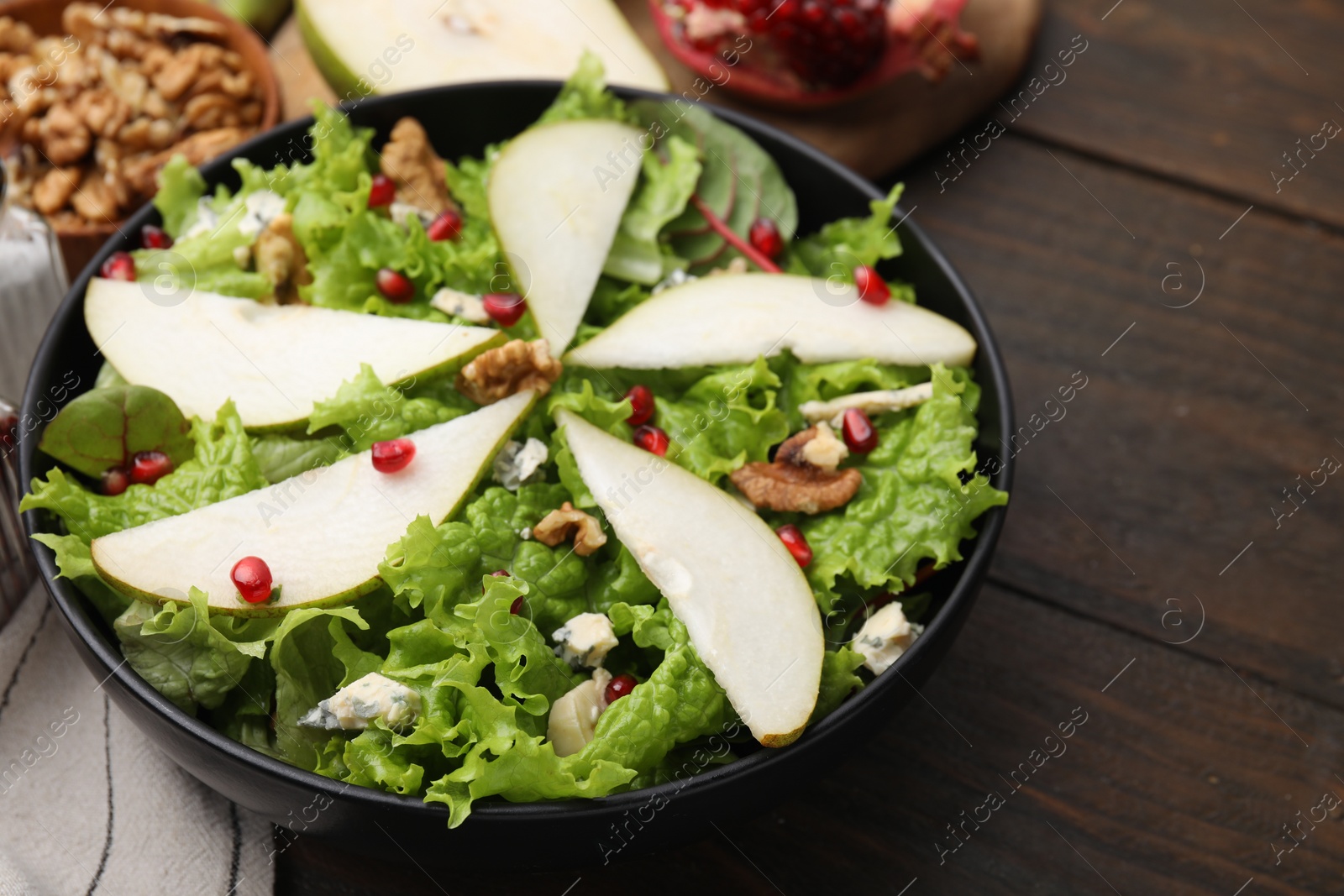 Photo of Delicious pear salad in bowl on wooden table, closeup