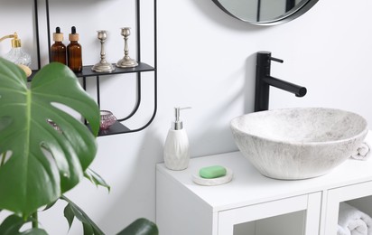 Different bath accessories and personal care products near sink on bathroom vanity