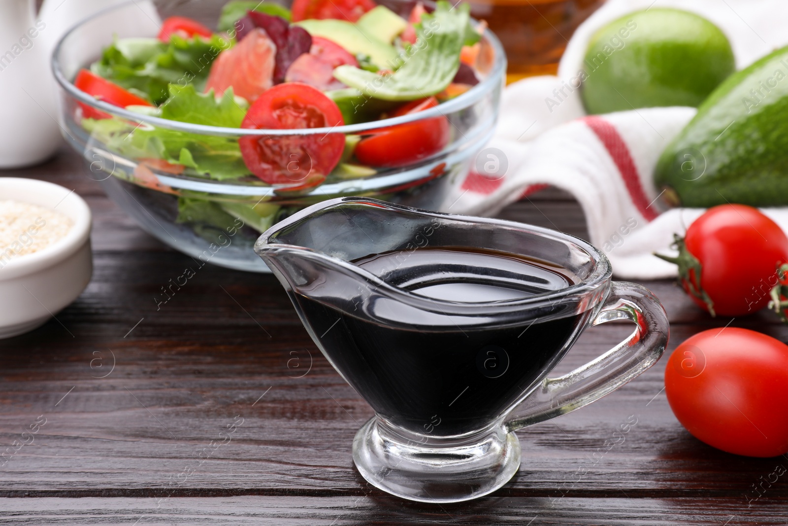 Photo of Tasty soy sauce, salad and ingredients on wooden table, closeup