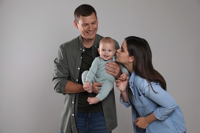 Photo of Happy family. Couple with their cute baby on grey background