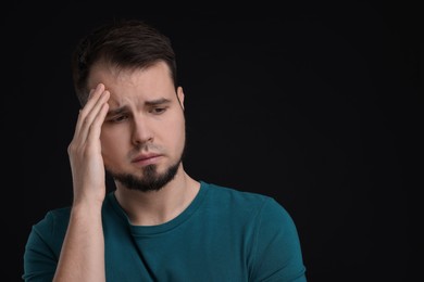 Portrait of sad man on black background, space for text