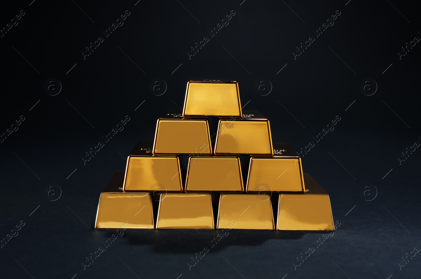 Photo of Stack of shiny gold bars on black background