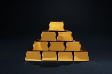 Stack of shiny gold bars on black background