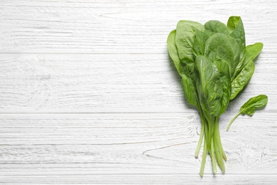 Photo of Fresh green healthy spinach on white wooden table, top view. Space for text