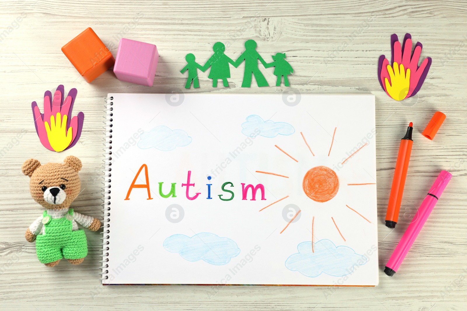 Photo of Flat lay composition of notebook with word Autism and toys on white wooden table