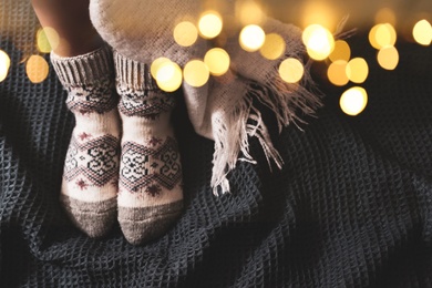 Image of Woman in warm socks on knitted blanket, top view. Space for text