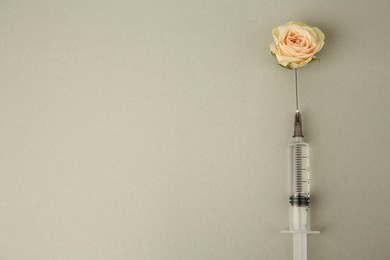 Medical syringe and rose flower on light grey background, flat lay. Space for text