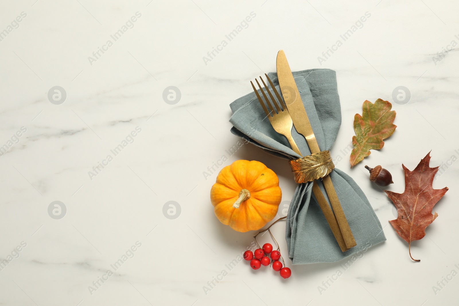 Photo of Cutlery, napkin and autumn decoration on white marble background, flat lay with space for text. Table setting