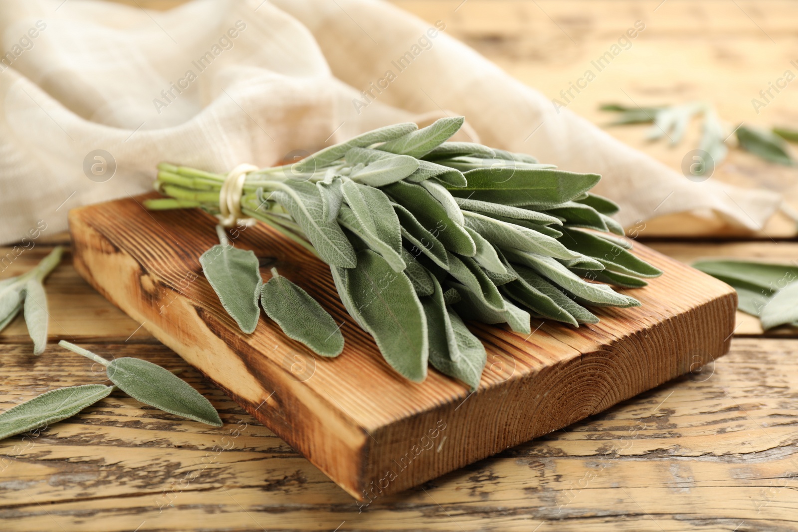 Photo of Board with fresh green sage on wooden table, closeup