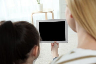 Mother and her daughter using video chat on tablet at home. Space for text