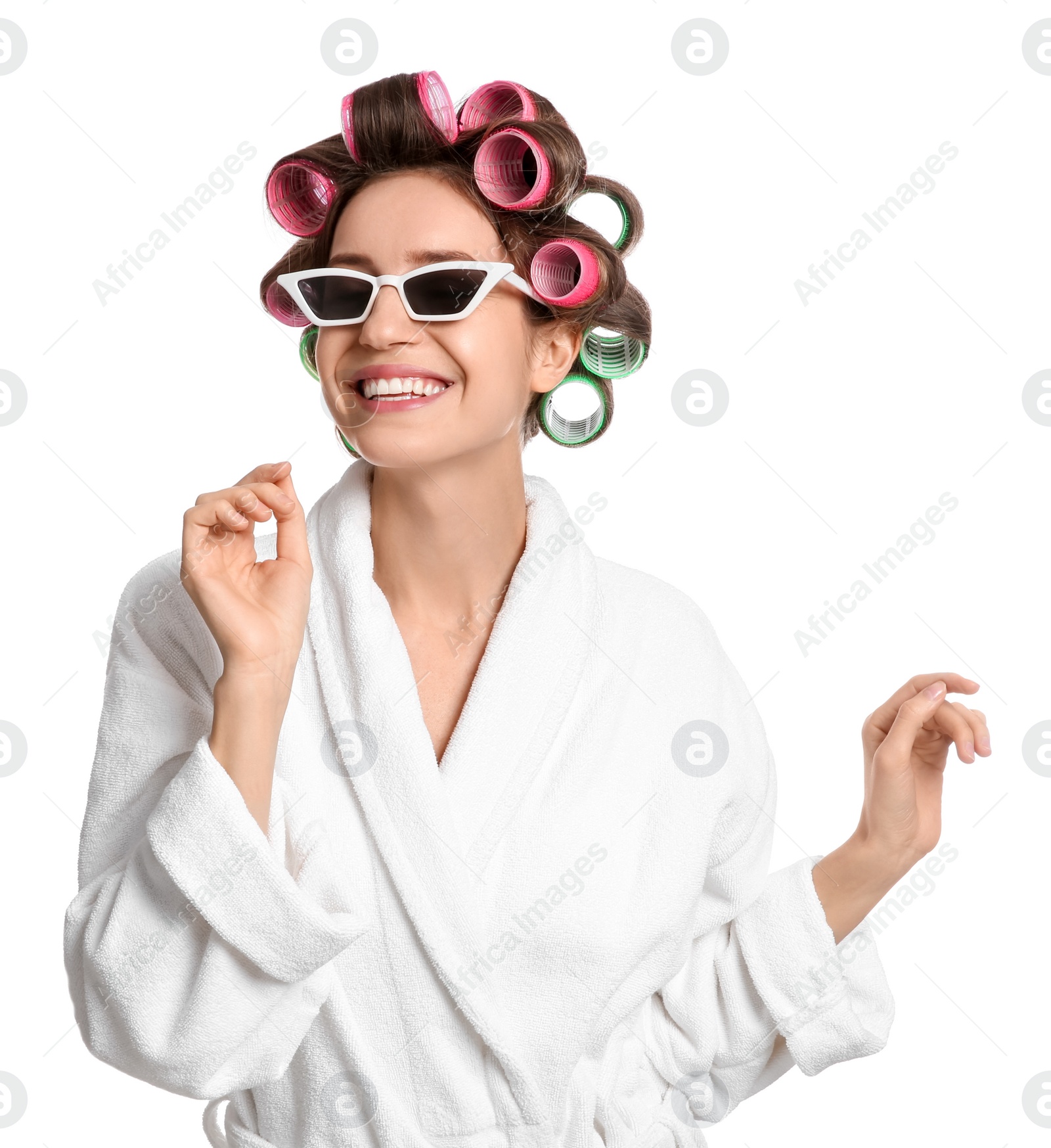 Photo of Beautiful young woman in bathrobe with hair curlers and sunglasses on white background