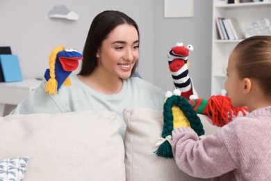 Photo of Happy mother and daughter playing with sock puppets together at home