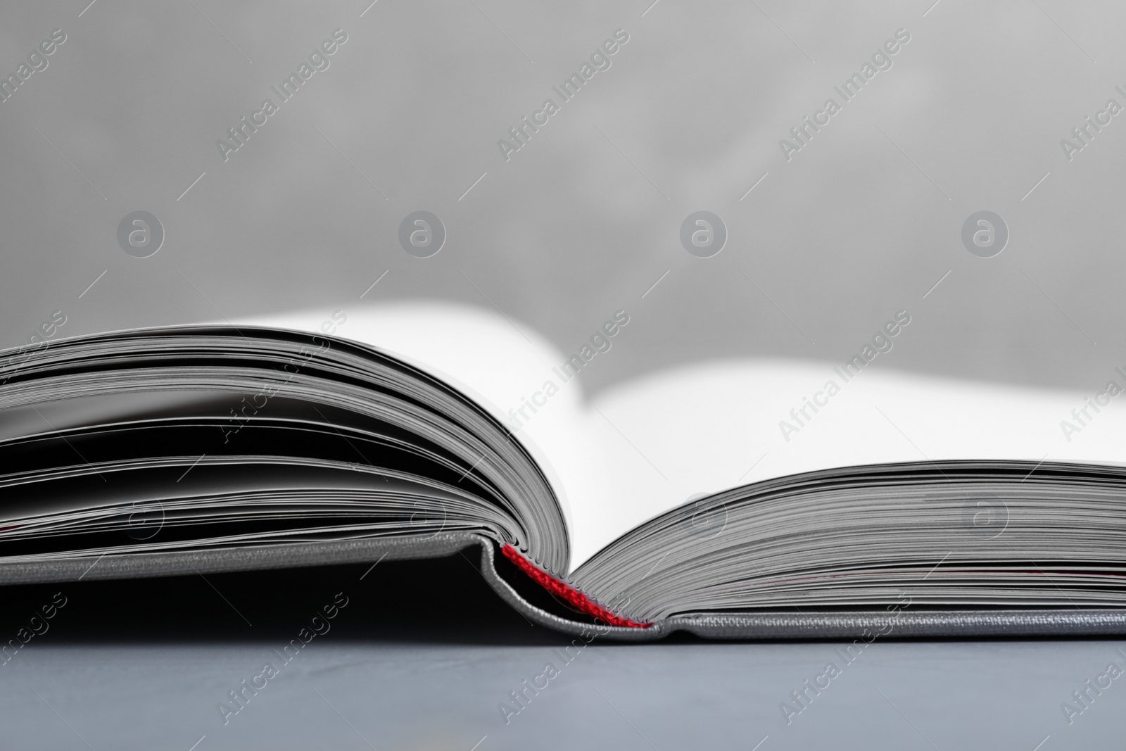 Photo of Open book with hard cover on grey table, closeup